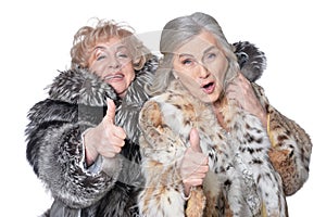 Portrait of senior women in fur coats with thumbs up