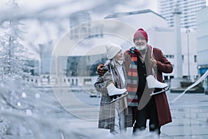 Portrait of seniors with ice skates at outdoor ice skating rink at the winter.