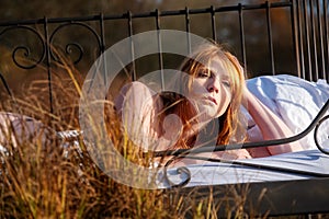 Portrait of an sensual, attractive, content, young, sexy redhead woman lying relaxed in bed, enjoying the nature in the orange