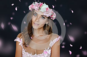 Portrait of a sensual beautiful girl in a pink dress and a wreath of flowers, beauty, close-up, on a dark background, with flying