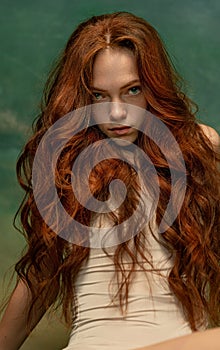 Portrait of sensual beautiful redhead girl with long curly hair. Gorgeous hair and deep green eyes. Concept of beauty