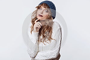 Positive blond woman in sweater and hat isolated on white background