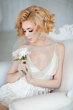Portrait of the sensual and tender blonde sitting in a whit