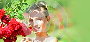 Portrait of sensual woman in spring background. Banner for website header. Happy girl in a garden with red roses