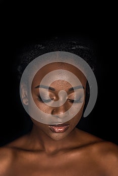 portrait of sensual young african american woman with water drops on face posing with closed eyes