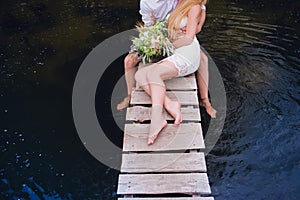 Portrait of a sensual young couple hugging on a wooden bridge