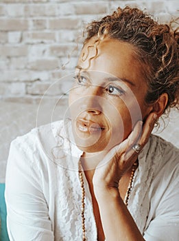 Portrait of serene woman looking outside the window at home having relax time sitting on the couch. Happy and confident female