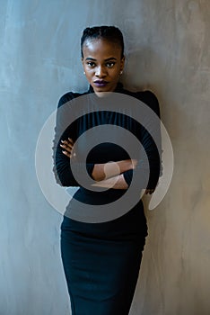 Portrait of a serious african or black american woman with arms folded standing over gray background and looking at camera