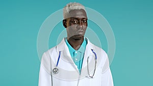 Portrait of serious afro doctor in professional medical white coat showing rejecting head gesture, disapproving sign