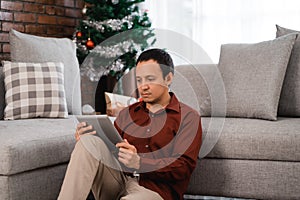 Portrait of serious asian young man sitting on floor front of co