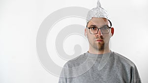 Portrait of serious attractive man in foil hat and glasses. Emotional handsome guy with a tinfoil helmet to the brains on his head