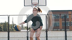 Portrait of serious attractive woman basketball player in uniform tossing, juggling basketball between hands on indoor