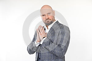 Portrait of serious bald middle-aged businessman in grey checkered jacket, vest, white shirt, standing, folding hands.