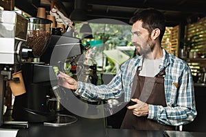 Portrait of serious barista man making coffee while working in street cafe or coffeehouse outdoor