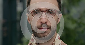 Portrait of serious bearded guy with stylish neckerchief looking to camera. Close up of handsome man wearing glasses