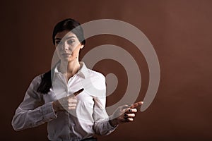 Portrait of serious brunette business woman pointing her finger to the side in studio on brown background with copyspace.