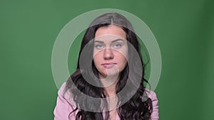 Portrait of serious brunette businesswoman in pink jacket turns head negatively to deny or disagree on green background.