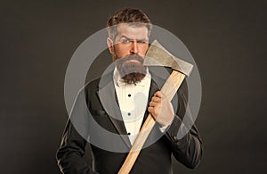 Portrait of serious brutal man holding axe at bearded face dark background, barbershop