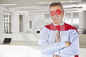 Portrait of serious businessman in superhero costume in office