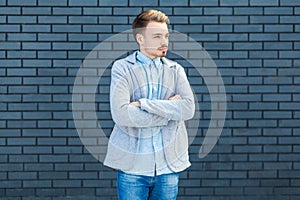 Portrait of serious calm handsome young blonde man in casual style standing with crossed arms and looking away with relaxed face