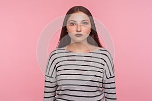 Portrait of serious calm young woman in striped sweatshirt looking at camera with unsmiling earnest expression