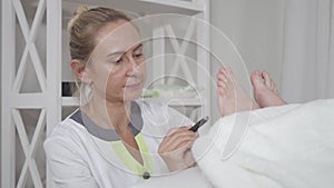 Portrait of serious Caucasian acupuncturist heating female feet with moxa. Adult professional woman with brown eyes