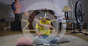 Portrait of serious Caucasian boy in VR googles moving away something invisible. Schoolboy in yellow T-shirt and blue