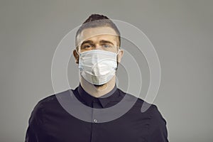 Portrait of serious caucasian man in face medical mask isolated on grey