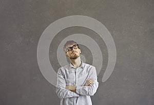 Portrait of a serious caucasian young man with a pensive expression on a gray background.