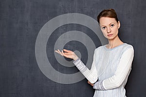 Portrait of serious concentrated girl pointing with hand at left