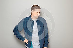 Portrait of serious concentrated man holding hand on hip and thinking