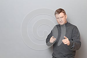 Portrait of serious concentrated man pointing with fingers at you
