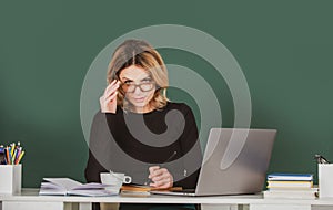 Portrait of serious concentrated teacher or female tutor working at table in college or high school. Young women student