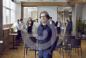 Portrait of serious confident business man standing in office against background of his office team.