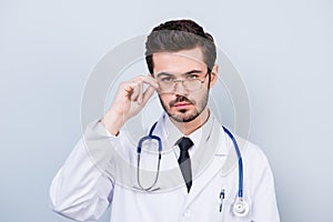 Portrait of serious confident young doctor touching his glasses. Close up portrait of serious handsome trainee. Touching eyeglasse