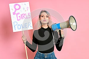 Portrait of serious and confident young feminist girl isolated over pink background