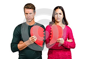 Portrait of serious couple holding cracked heart shape