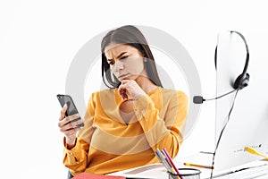 Portrait of serious customer supporter woman holding smartphone while working in call center