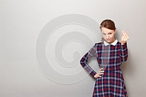 Portrait of serious discerning girl making money gesture with fingers