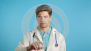 Portrait of serious doctor in professional medical white coat showing rejecting gesture disapproving with no finger sign