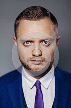 Portrait of serious fashionable handsome man in blue suit looking at camera