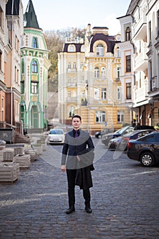 Portrait of a serious fashionable handsome man in a blue suit and tie is holding a coat in the streets of the city, vertically