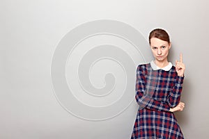 Portrait of serious focused girl pointing up with index finger