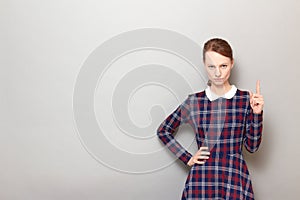 Portrait of serious focused girl pointing up with index finger