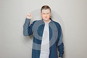 Portrait of serious focused rebellious man raising fist up