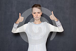 Portrait of serious focused woman raising thumbs up