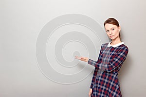 Portrait of serious girl pointing with one hand at copy space