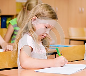 Portrait of a serious girl who writes in a exercise book during