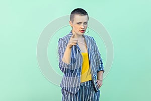 Portrait of serious handsome beautiful short hair young stylish woman in casual striped suit standing, warning and looking at