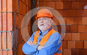 Portrait serious handsome builder in hard hat working on house construction. Male engineer or architect at building site